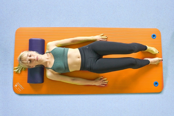 Eine Frau liegt mit geschlossenen Augen auf eine Yogamatte