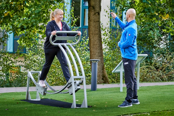 Therapeut erklärt Frau das Trainingsgerät Therapeut erklärt Frau das Trainingsgerät